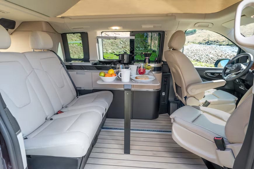 Interno van camperizzato con tavolo e sedili beige